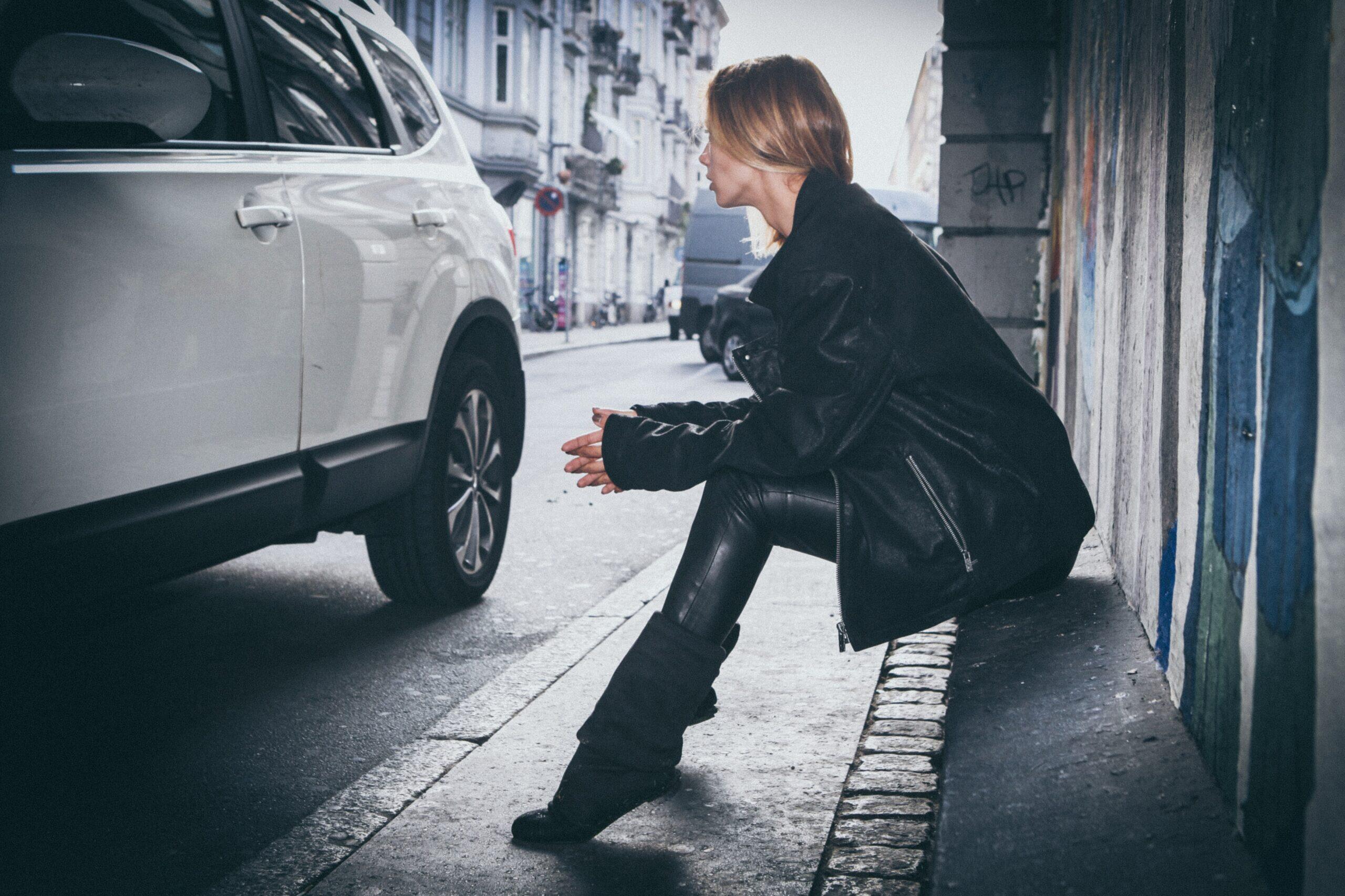 woman sitting on gray concrete sidewalk