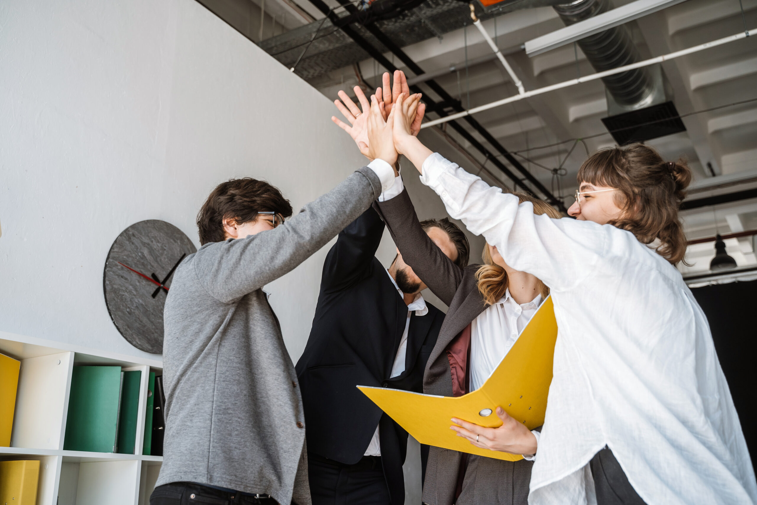 cheerful young group of people standing in the office and giving high five scaled