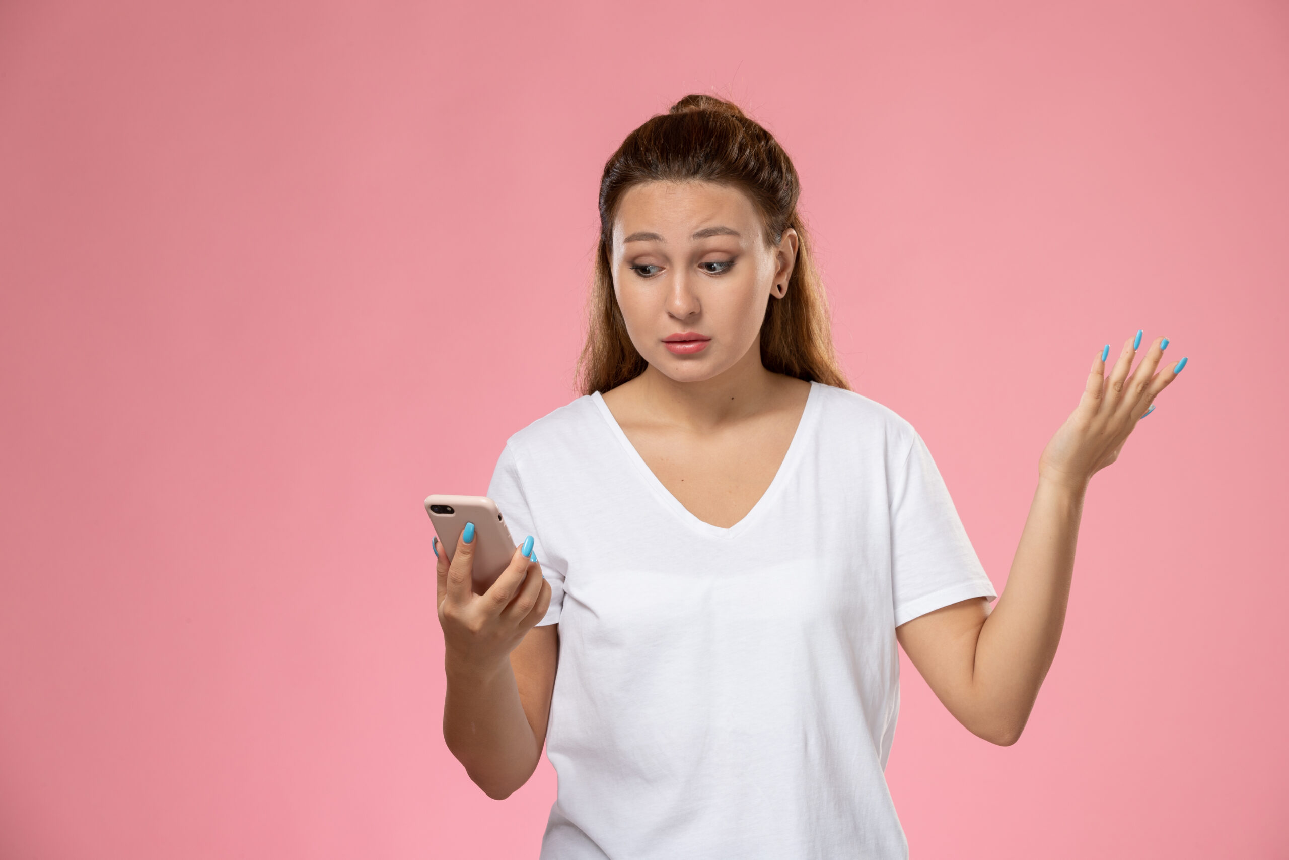 front view young attractive female in white t shirt using her phone on pink background scaled