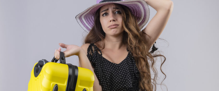 upset young beautiful traveler girl dress polka dot summer hat holding suitcase looking camera with sad expression face standing white background 1